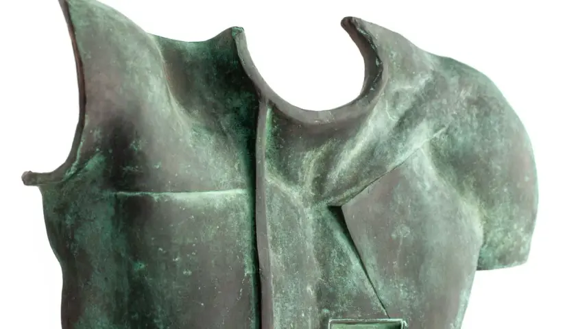 Fragment rzeźby z brązu przedstawiający tors z zieloną patyną.