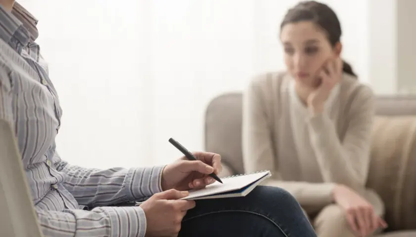 Psycholog notuje podczas sesji. Zastanawiasz się, ile zarabia psycholog? To zależy od wielu czynników, ale warto wiedzieć, że praca ta jest wymagająca i satysfakcjonująca.