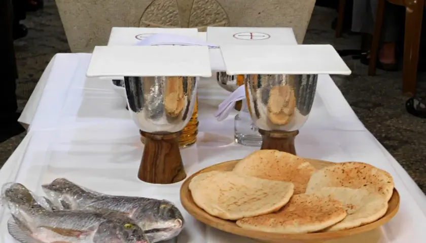 Dwa ryby i płaskie chleby na stole, symbolizujące rozmnożenie chleba i ryb.