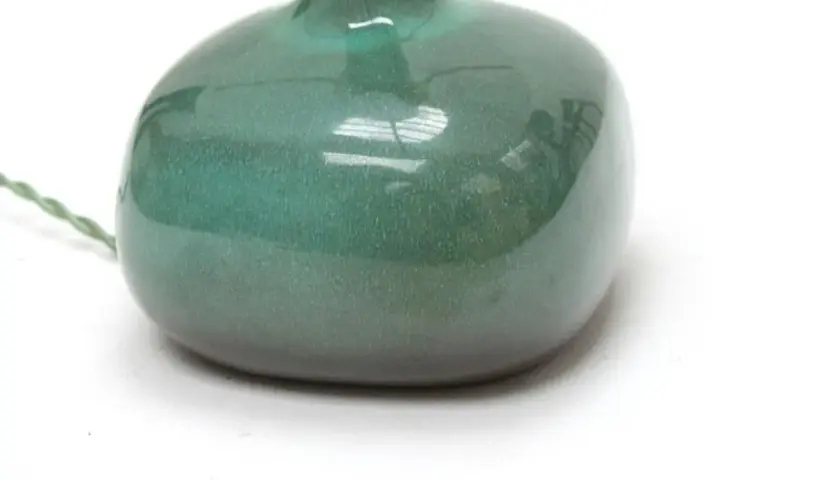 Base d'une lampe en céramique verte, œuvre de Jacques et Dani Ruelland, avec un fil électrique torsadé.