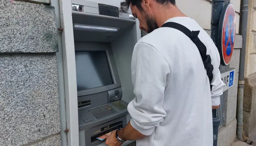 Un homme retire de l'argent à un distributeur automatique. Il suit les étapes pour comment retirer de l'argent.