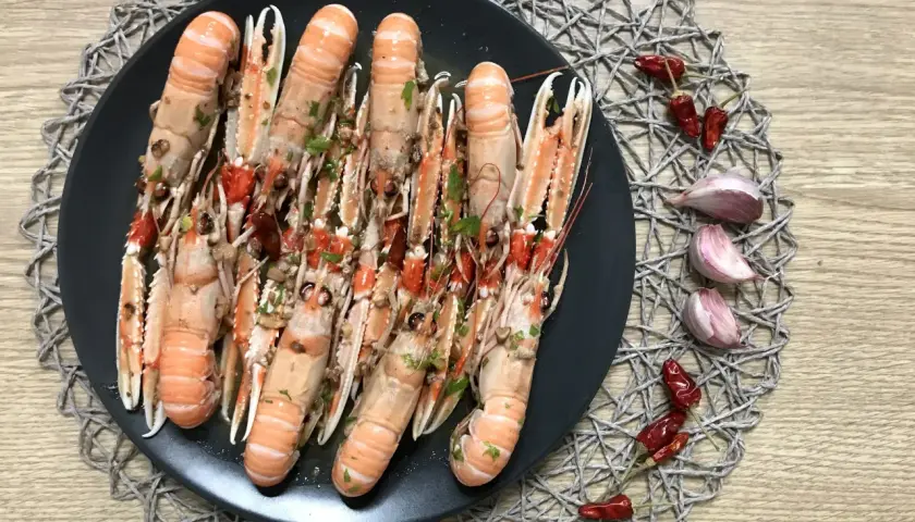 Plato de cigalas al ajillo, con guindillas y ajos.