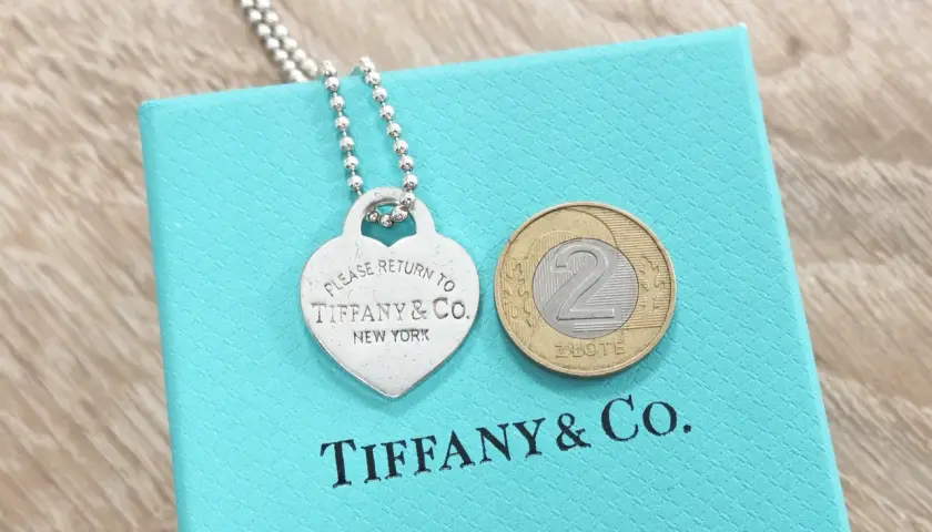Srebrne serce z napisem "Please Return to Tiffany & Co. New York" na turkusowym pudełku Tiffany & Co. z monetą 2 złote.