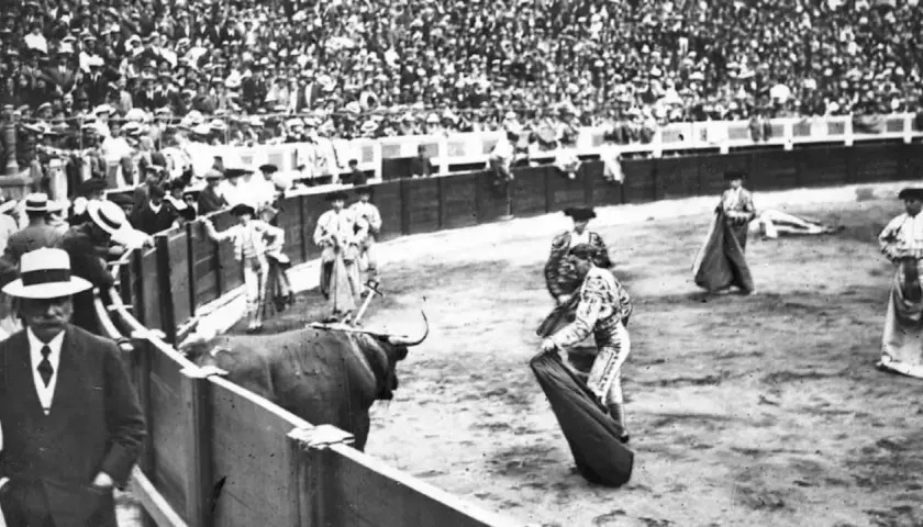 En la plaza, un toro bravo se prepara para la cornada. Joselito el gallo, con su traje de luces, se enfrenta al animal ante una multitud expectante.