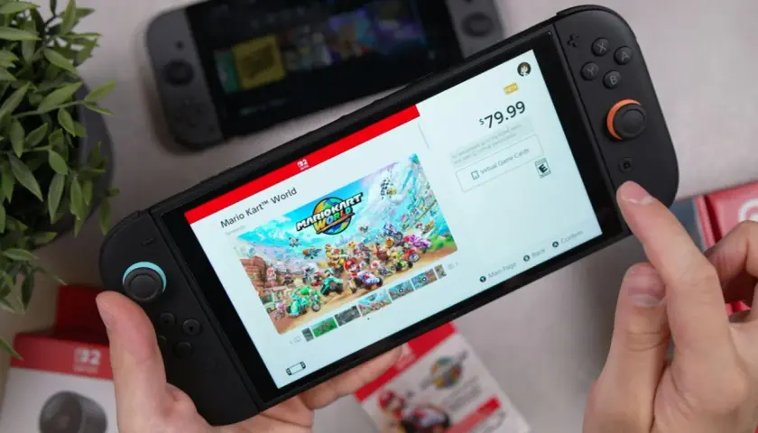 Ręce trzymają konsolę Nintendo Switch, na ekranie której wyświetla się okładka gry Mario Kart World. To może być najlepsza gra na Nintendo Switch!