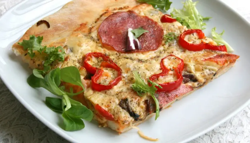 Proste ciasto na pizzę zawsze wychodzi, oto kawałek z salami, papryką i serem, udekorowany świeżą sałatką.