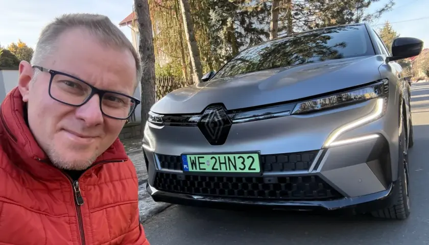 Mężczyzna w czerwonej kurtce robi selfie z nowym Renault Megane E-Tech.