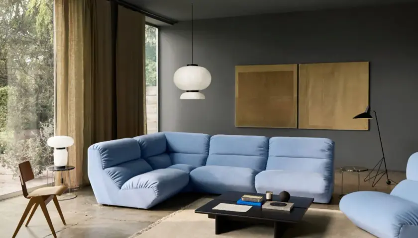 Moderne Wohnzimmer-Ideen: Hellblaues Ecksofa, dunkle Wandfarbe, goldene Kunstwerke und ein minimalistischer Stil.