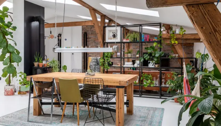Jasne, oto propozycja:

Wnętrze z drewnianym stołem i mnóstwem roślin, tworzące przytulny biophilic design.