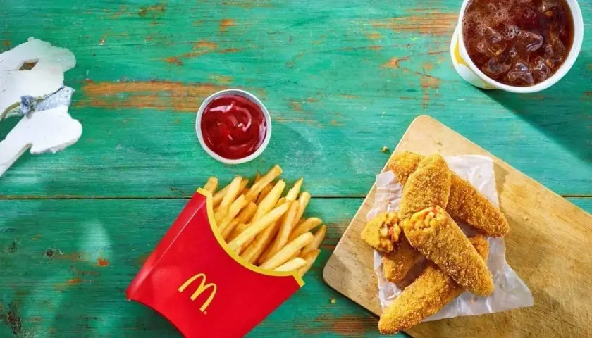 Chrupiące nuggetsy z serem i kukurydzą – to jest wege w maku! Obok frytki, ketchup i napój.