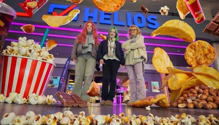 Trzy dziewczyny przed kinem Helios, otoczone przez gigantyczne przekąski. Zastanawiasz się, ile kosztuje mały popcorn w Heliosie?
