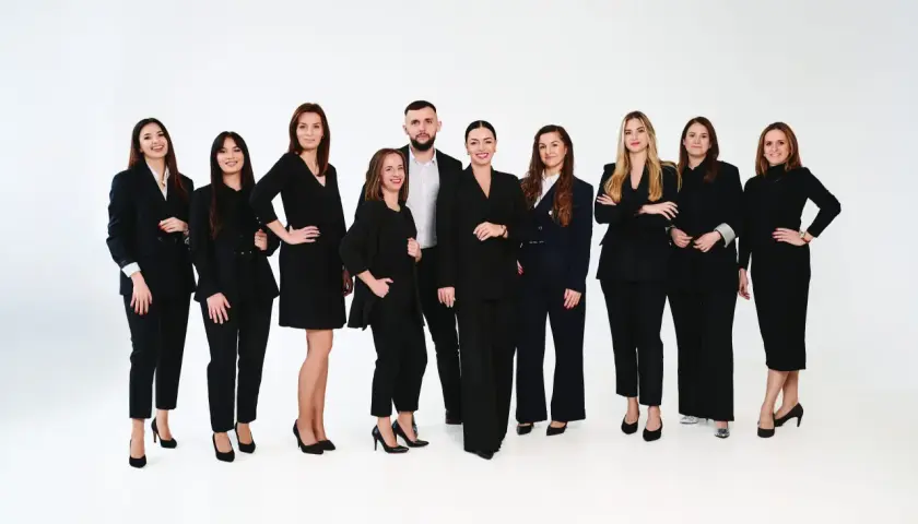 Grupa profesjonalistów w czarnych garniturach na białym tle.