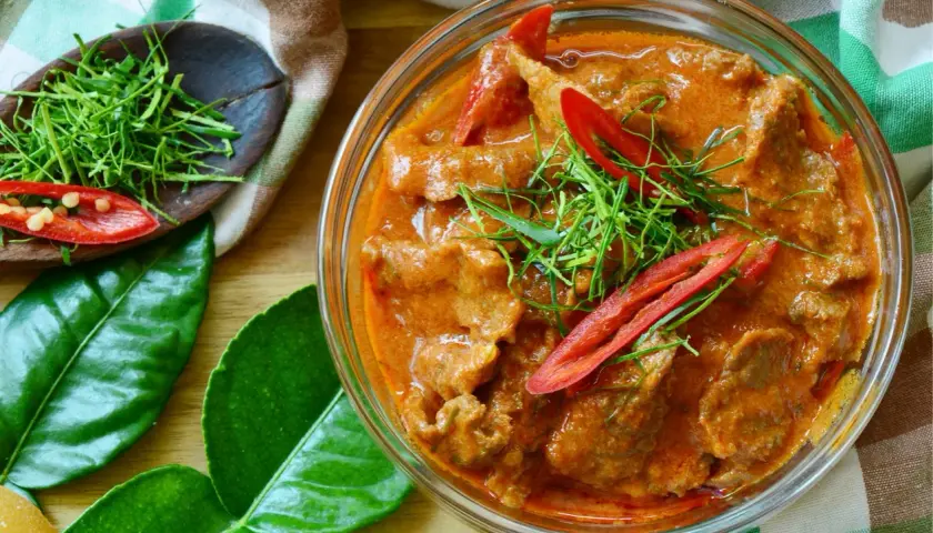 Un délicieux boeuf curry rouge, garni de piments et d'herbes fraîches, prêt à être dégusté.