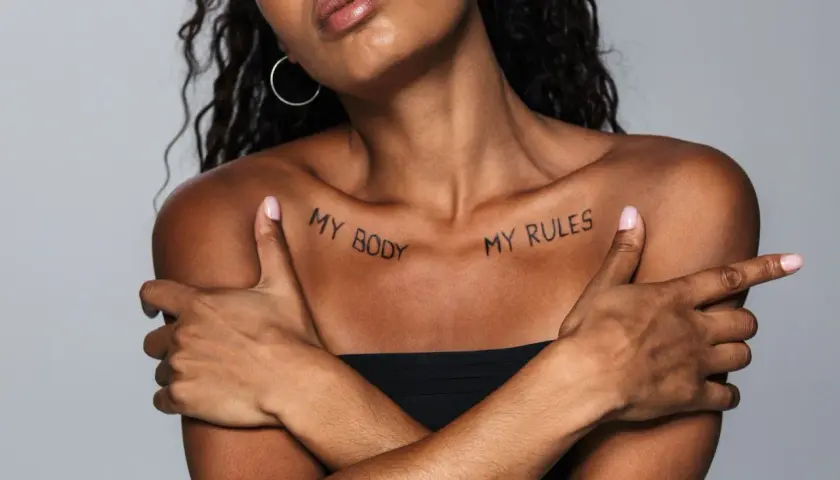 Kobieta z tatuażem na obojczyku: "MY BODY MY RULES". Wyrazisty napis, podkreślający siłę i autonomię.