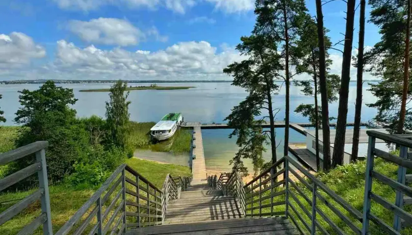 Idealne miejsce na mazury na weekend. Drewniane schody prowadzą do jeziora, gdzie cumuje statek.