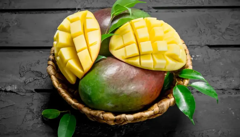 Koszyk z dojrzałymi mango, jedno przekrojone w kostkę. Czy zastanawiałeś się nad mango indeks glikemiczny?