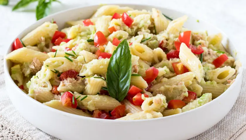 Penne con tonno e avocado, un piatto fresco e colorato con pomodorini e basilico.