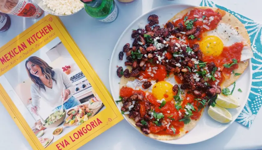 Deux œufs sur le plat, haricots noirs et sauce tomate sur tortillas, inspirés par le livre "Mexican Kitchen" d'Eva Longoria. Un plat de huevos rancheros savoureux.