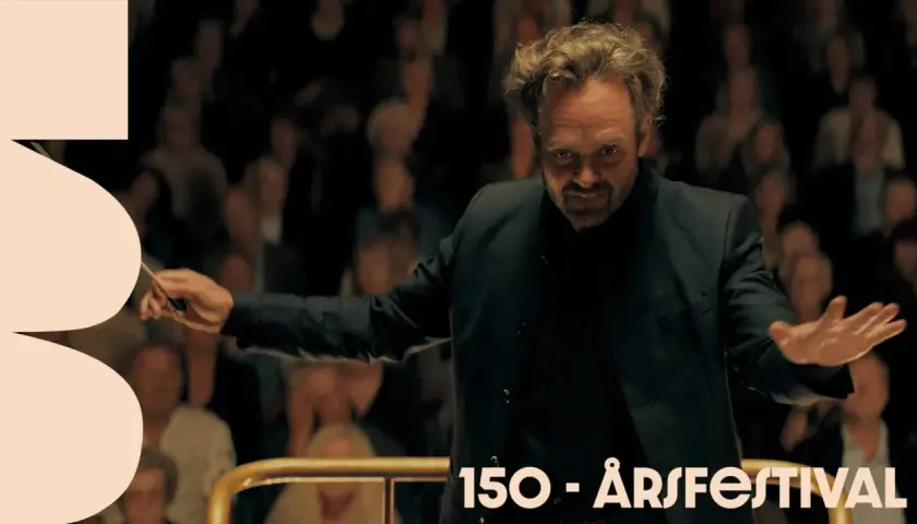Dirigenten leder orkestern med passion, som om han vore med i rollistan i Hugo Cabret. Publiken ser på.