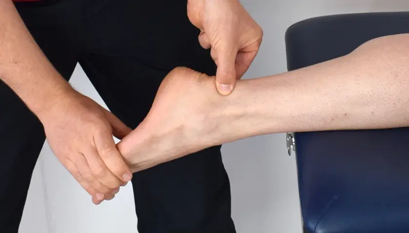 Mains appliquant un massage sur le tendon d'Achille d'une cheville.