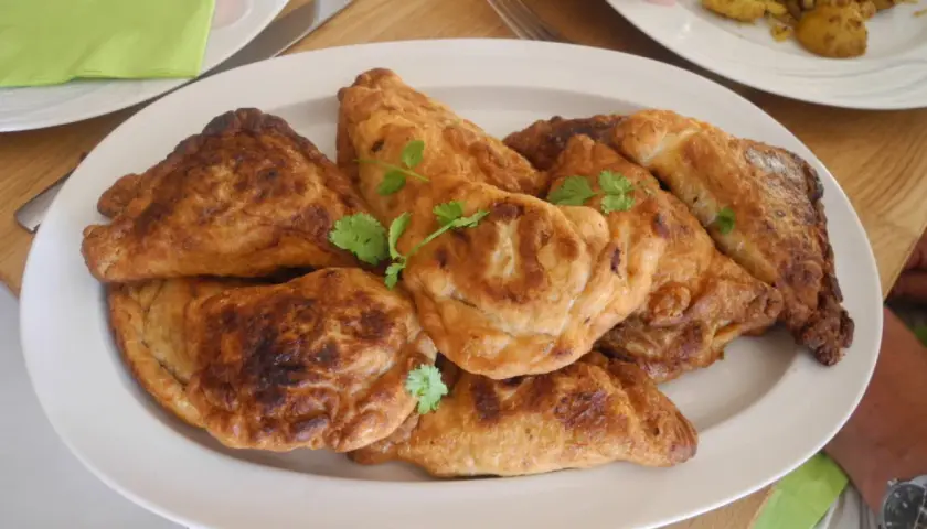 En tallrik med gyllene, friterade samosas, perfekt för ett samosa recept. Garnerade med färsk koriander.