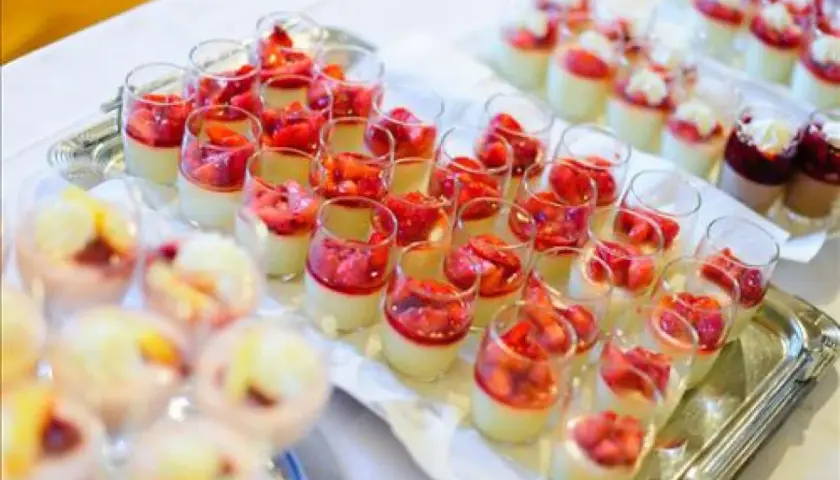Plateau de mini dessert pour buffet : verrines crémeuses garnies de fraises fraîches et d'une touche de coulis rouge.