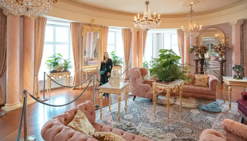 Elegancki salon z różowymi sofami i kryształowymi żyrandolami. Marzenie o noclegu w zamku staje się rzeczywistością.