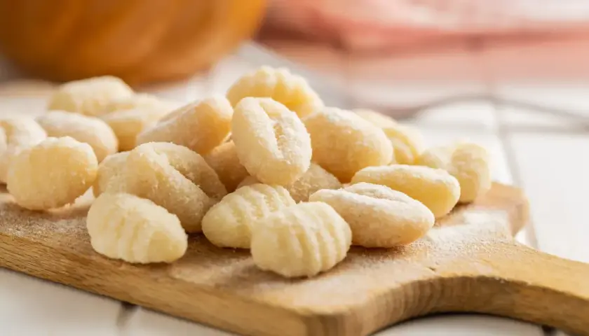 Gnocchis faits maison sur une planche en bois. La question "quelle pomme de terre pour gnocchi" est résolue avec ces petites bouchées parfaites.