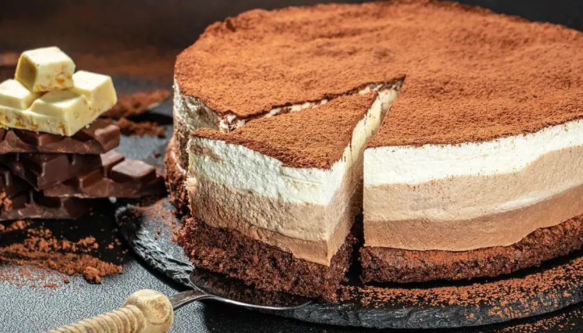 Tarta tres chocolates, con capas de mousse de chocolate blanco, con leche y negro, espolvoreada con cacao.