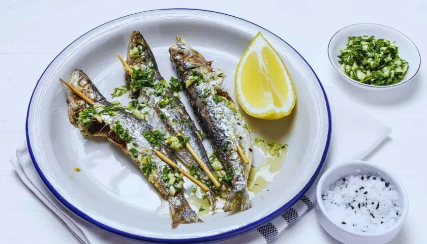Tres sardinas a la plancha, doradas y jugosas, con perejil y ajo picado, acompañadas de limón y sal.