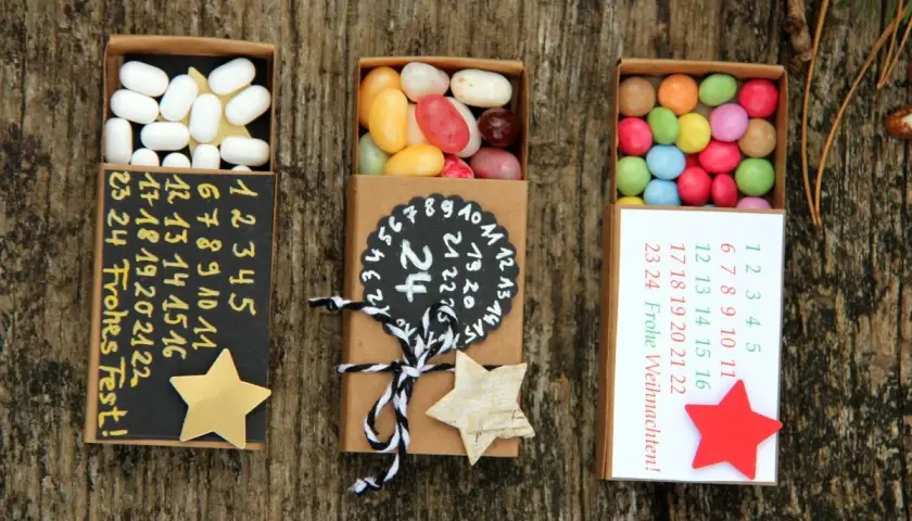 Kleine Schachteln zum Adventskalender to go basteln, gefüllt mit Süßigkeiten und nummerierten Tagen.
