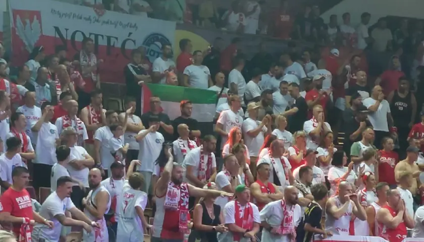 Tłum kibiców w biało-czerwonych barwach, z flagami i szalikami. Widać transparent z napisem "NOTEĆ". Atmosfera przypomina mecz, gdzie Polska rywalizuje z Izraelem.