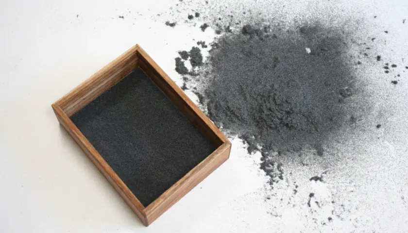 Un tas de flocage qui s'effrite s'est répandu à côté d'un plateau en bois rempli de la même matière.