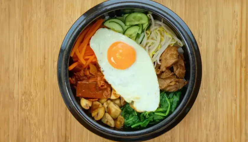 Kolorowe bibimbap, klasyczne danie kuchni koreańskiej, z jajkiem sadzonym, warzywami i mięsem.