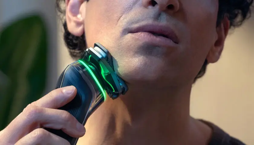 Mężczyzna goli twarz golarką Philips z zielonym podświetleniem.
