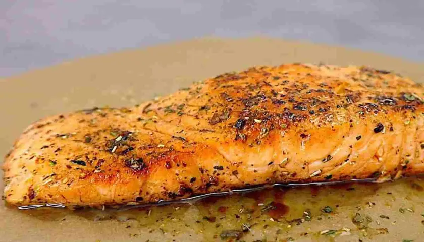 Succulento salmone in padella, dorato e profumato con erbe aromatiche, adagiato su carta da forno.