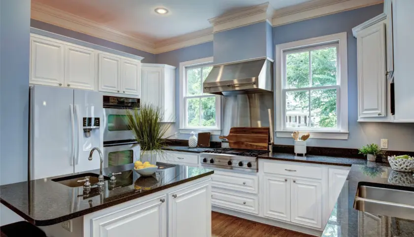 A bright kitchen with white cabinets and granite countertops. Learn how to care for granite to keep it looking its best.