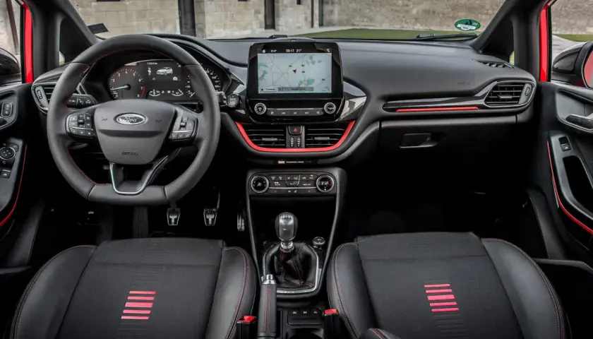 Interior deportivo del Ford Fiesta ST Line. Volante, asientos y detalles rojos resaltan en este habitáculo moderno.