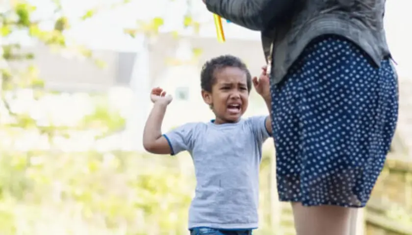 Un niño de 4 años, mi hijo, no obedece y pega. Llora y se enfada mientras su madre intenta calmarlo.
