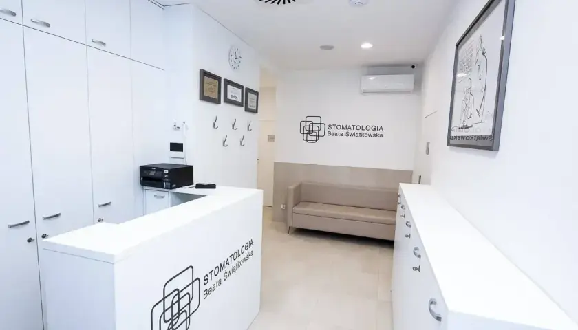 Nowoczesna recepcja gabinetu stomatologicznego z kanapą i logo.