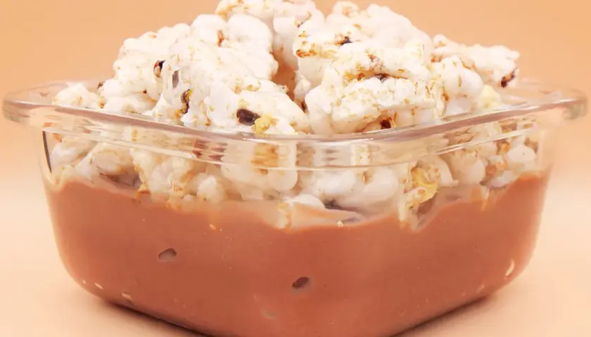 Pudding ryżowy fit w szklanej miseczce, przykryty chrupkami ryżowymi. Idealny na lekki deser.