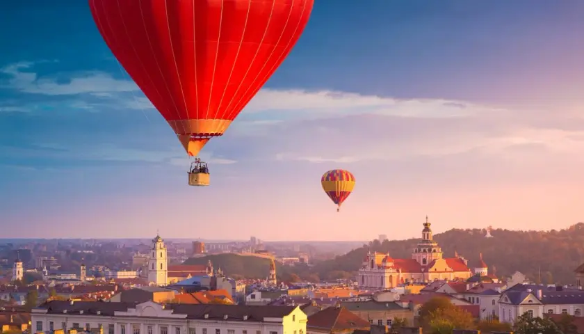Widok na Wilno z lotu ptaka. Dwa balony unoszą się nad miastem o zachodzie słońca, oferując niezapomniane wrażenia z podróży "Wilno w jeden dzień".