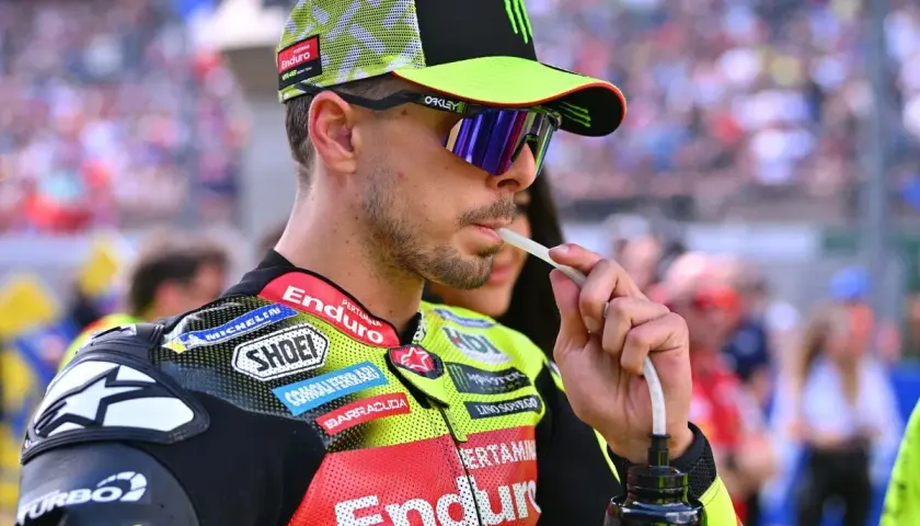 Fabio Di Giannantonio, piloto de MotoGP, bebe de una botella con un tubo, luciendo su casco y gafas de sol.