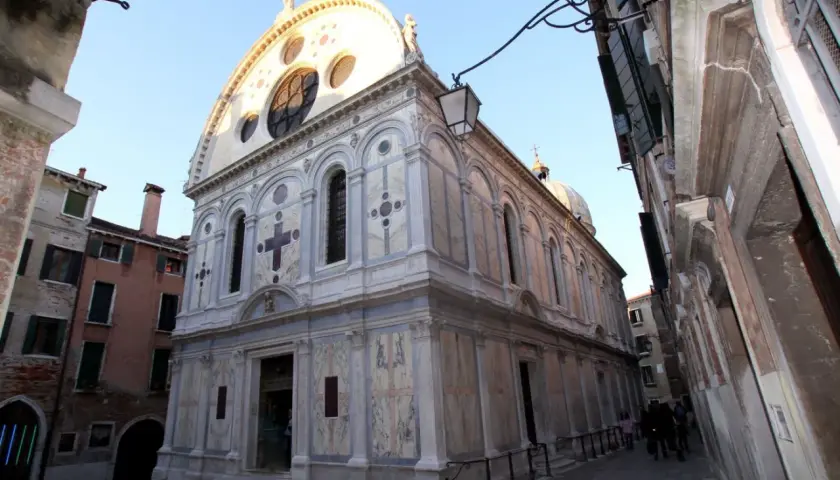 La façade en marbre de Santa Maria dei Miracoli à Venise, ornée d'une grande rosace et d'une croix.