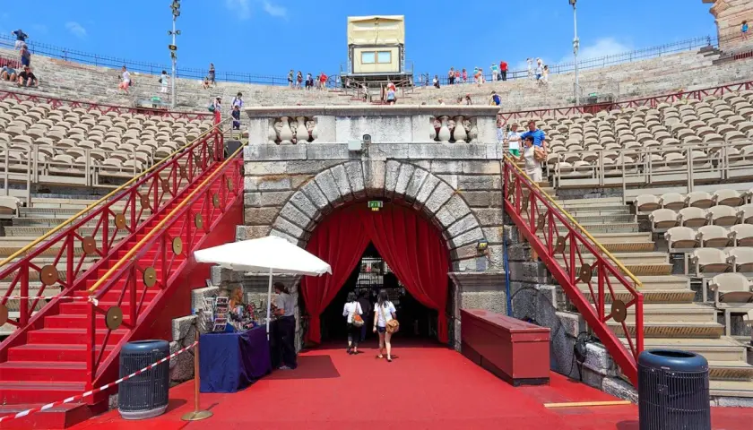 L'Arène de Vérone, avec ses gradins de pierre et ses escaliers rouges, accueille des visiteurs sous un ciel bleu.