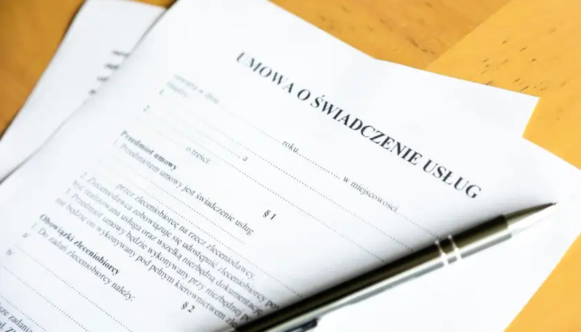 Umowa o świadczenie usług. Czy świadczenie integracyjne wlicza się do stażu pracy? Długopis leży na dokumencie.