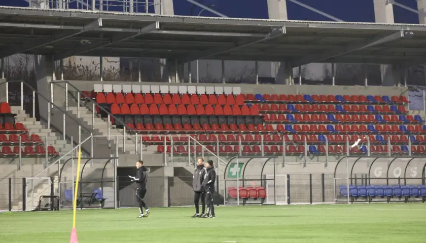 Piłkarze Polonii Bytom trenują na nowym stadionie. Puste trybuny z czerwonymi i niebieskimi krzesełkami czekają na kibiców.