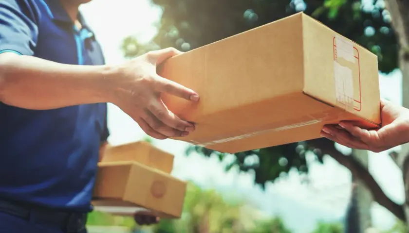 Ein Lieferant übergibt ein Paket. Hoffentlich ist das Paket angekommen und nicht verloren gegangen.