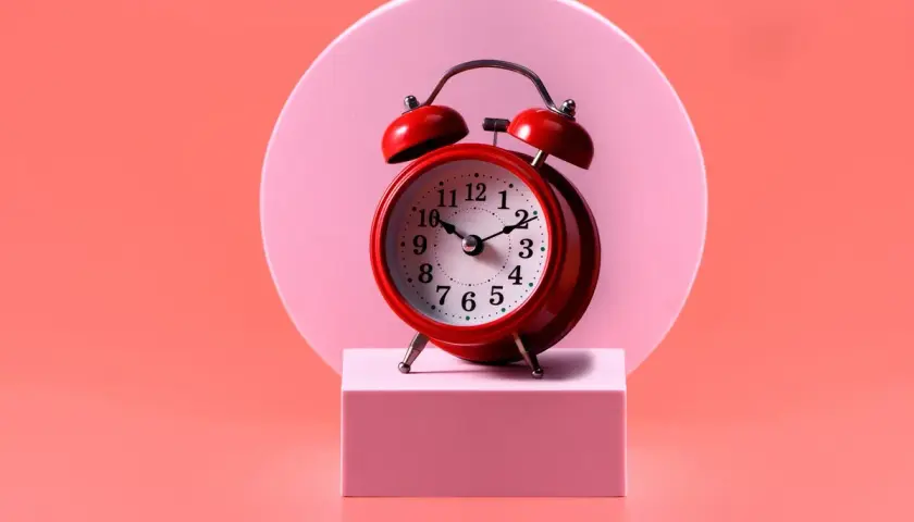 Reloj rojo sobre pedestal rosa. El 0909 significado espiritual nos recuerda la importancia del tiempo y la conexión.