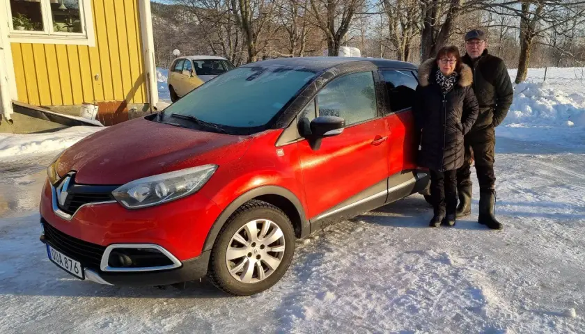 Ett par står bredvid en röd Renault Captur med frost på vindrutan. Kanske ett problem med att starta bilen i kylan?